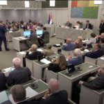 Op de foto is de vergadering van de Eerste Kamer te zien. Bij de interruptiemicrofoon staat senator A.J.A. Beukering van de fractie Beukering die een stemverklaring aflegt.