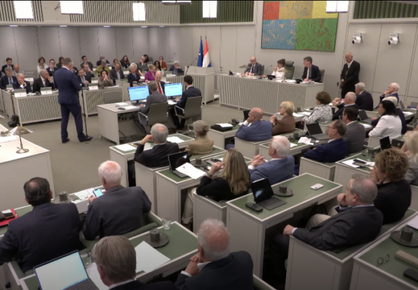 Op de foto is de vergadering van de Eerste Kamer te zien. Bij de interruptiemicrofoon staat senator A.J.A. Beukering van de fractie Beukering die een stemverklaring aflegt.